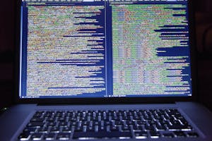 Laptop displaying source code with dual screens for software development.